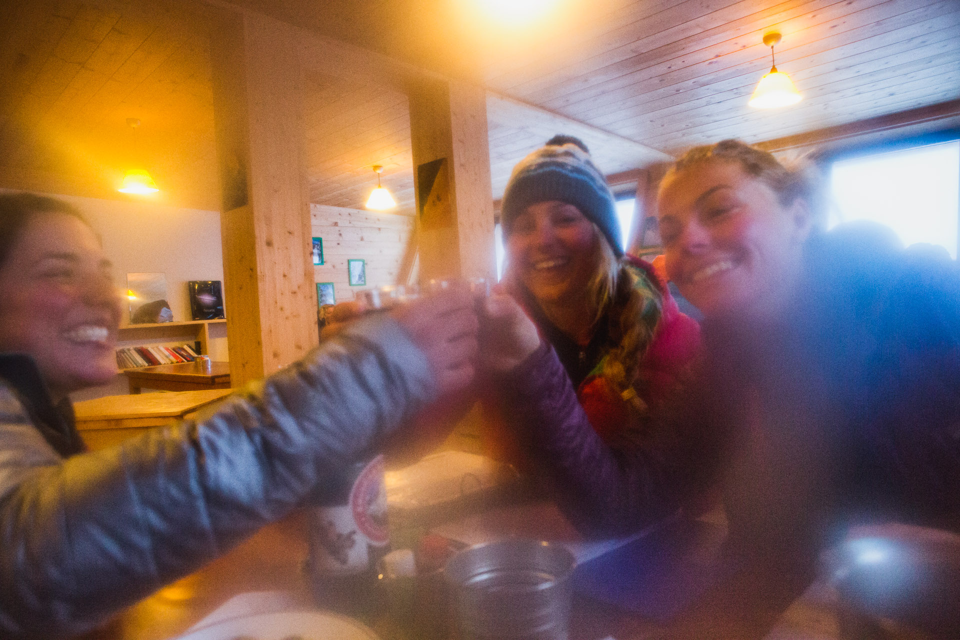Maria DeBari, Liz Daley and Bibi Pekarek clink wine glasses at the Argentiere Refuge after a cold day of touring. My lens was frozen and fogged. Chamonix, France.