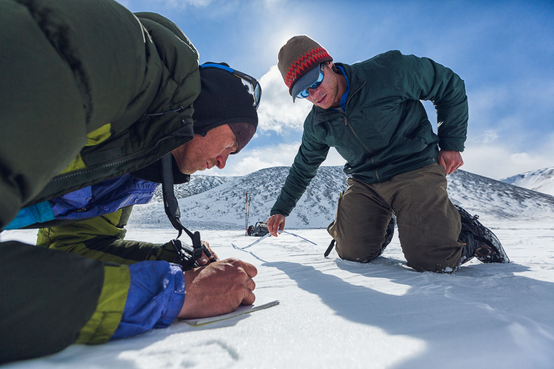 Gregg Treinish extends a ruler to measure the stride of a large felid track while Jason Wilmot records measurements. The pair concluded that this was probably a Snow Lepoard track.